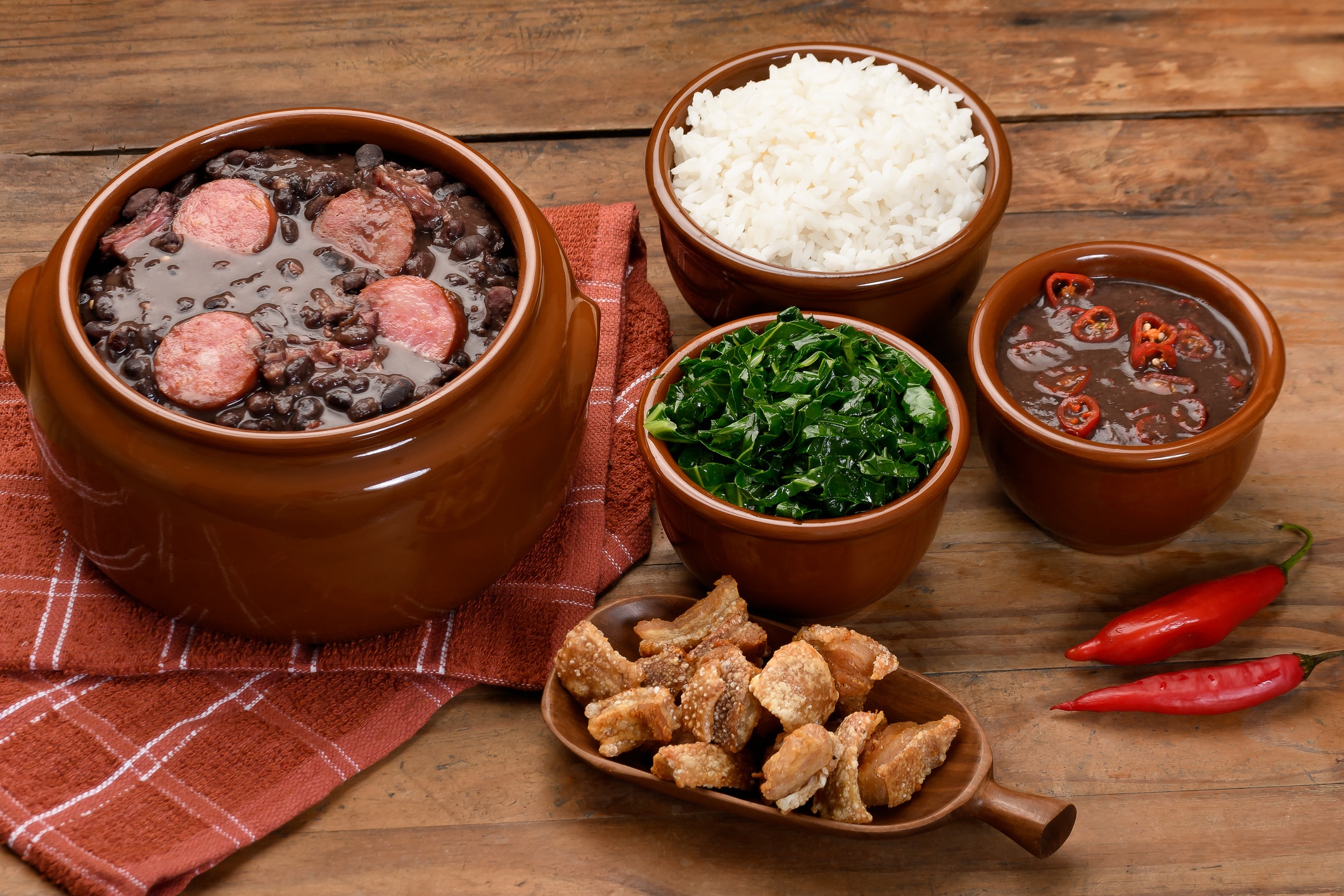 FEIJOADA IN A BROWN BOWL ON A WOODEN BASE, CABBAGE,
